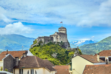 Fototapeta na wymiar Chateau Fort of Lourdes. Castle on a rock. Snowy mountain peaks. Blue sky with white clouds. City in the Hautes-Pyrénées, France