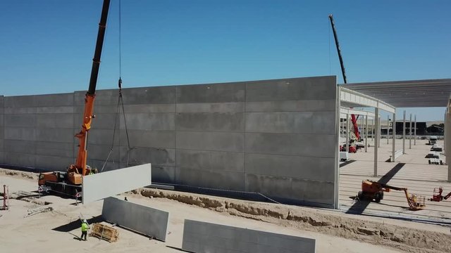 a&eacute;reo.colocaci&oacute;n de panel de hormig&oacute;n en el muro de una nave industrial en construcci&oacute;n .gr&uacute;a y operarios