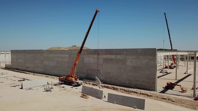 a&eacute;reo.colocaci&oacute;n de panel de hormig&oacute;n en el muro de una nave industrial en construcci&oacute;n .gr&uacute;a y operarios