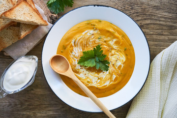 Carrot soup with sour cream and parsley in a bowl             