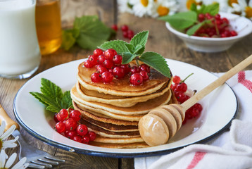 Stack of pancakes with honey and red currants       