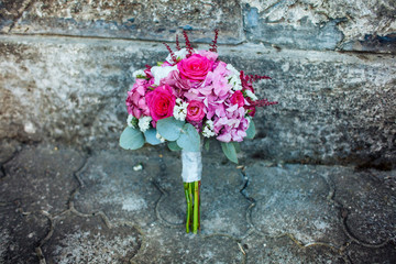Fototapeta na wymiar Beautiful wedding bouquet with pink roses and berries on the stone background