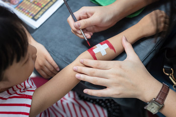 Asian little Chinese girl getting her arm painted a Swiss Flag