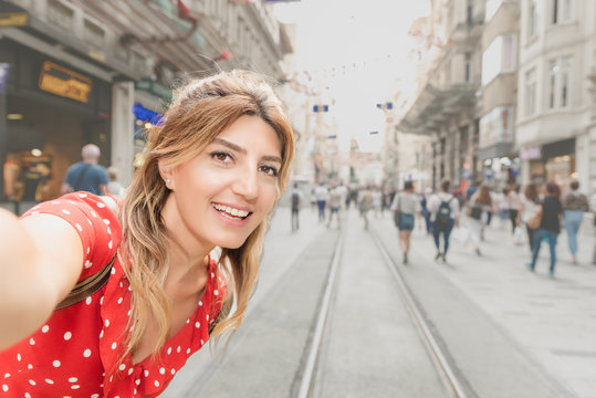 Beautiful woman in red dress takes selfie at Istiklal street