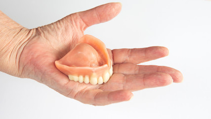 closeup of older womans hand holding dentures