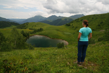 Fototapeta na wymiar A young woman admires the Lake of Love in Arkhyz.
