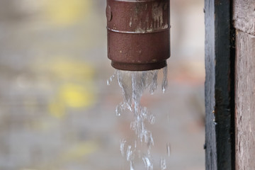 Naklejka na ściany i meble Rainwater flows from a drainpipe, close-up