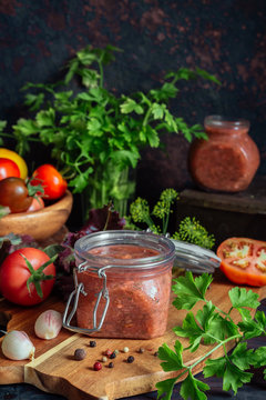 Tomato sauce and fresh tomatoes, garlic, dill, parsley on a dark wooden background still life in a vintage rustic style