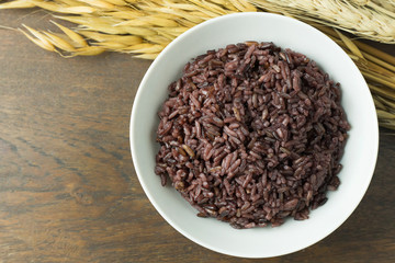 A Cooked rice berry ,Whole grain rice Thai black jasmine rice in bowl  on wood table.