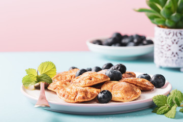 Dutch mini pancakes called poffertjes with blueberries, sprinkled with powdered sugar. Healthy food concept with copy space.