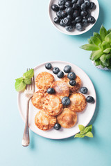 Dutch mini pancakes called poffertjes with blueberries, sprinkled with powdered sugar. Healthy food concept with copy space. Top view.
