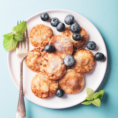 Dutch mini pancakes called poffertjes with blueberries, sprinkled with powdered sugar. Healthy food concept. Top view.