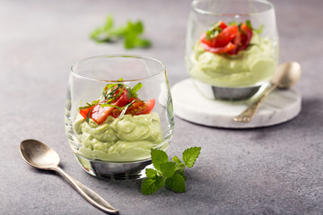 Fresh green avocado mousse with cherry tomatoes in glasses. Healthy vegan food concept with copy...