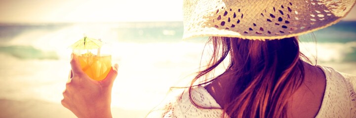 Brunette in straw hat holding cocktail