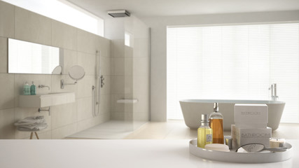 Spa, hotel bathroom concept. White table top or shelf with bathing accessories, toiletries, over blurred cream minimalist bathroom, modern architecture interior design