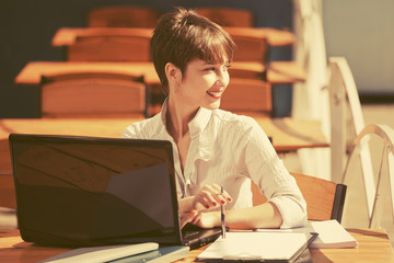 Young fashion business woman using laptop at sidewalk cafe