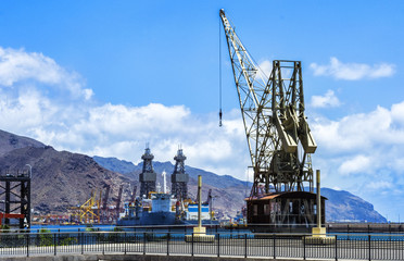Fototapeta na wymiar view of a seaport crane, with a view of mountains behind the image.