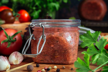 Tomato sauce and fresh tomatoes, garlic, dill, parsley on a dark wooden background still life in a vintage rustic style
