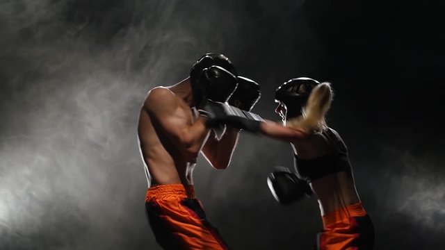 Sparring for kickboxing from the blow he falls to the floor. Smoke background. Slow motion
