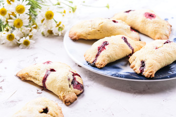 Homemade berries shortcakes, honeysuckle pastry pies on white cracked concrete background