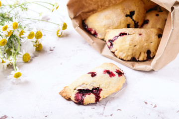 Homemade berries shortcakes, honeysuckle pastry and pastry pies in a paper bag to take-away on white cracked concrete background