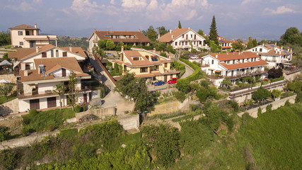 Aerial view of an isolated country houses. Around the buildings there are the countryside and the hills. This house is located on the hills of Tuscany, in Italy. On background sky and clouds.