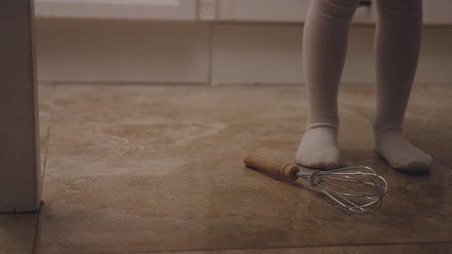 Close up of the girl's barefeet standing in the kitchen and kitchen stuff falling on the floor. Indoor