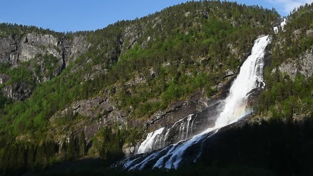 The waterfall Vidfossen just south of Odda in Hordaland, Norway. The morning sunshine creates a small rainbow in the fall.