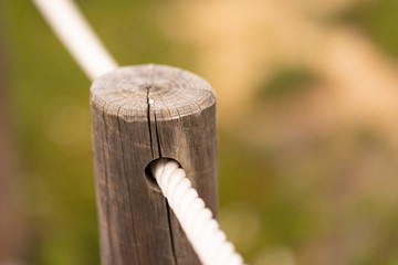 Detail of wood handrail on the sand with rope
