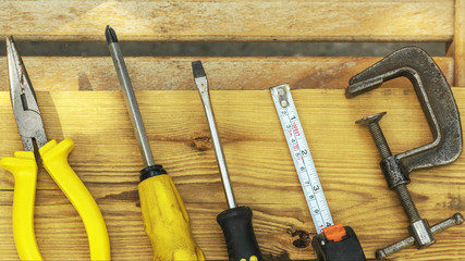 Assorted tools aranged on a wooden bench in yellow color