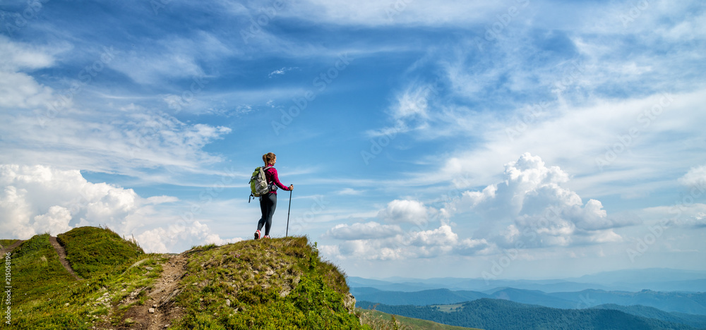 Wall mural young woman hiking in the mountains