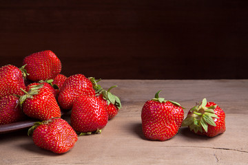 Strawberry fresh ripe sweet berry in clay plate on wooden background.