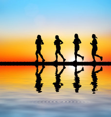 Fototapeta premium silhouette Young woman running on blurry sunset