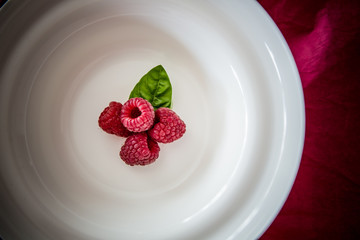  Red raspberry / Fresh ripe fruit served on a white plate. Flat lay minimalistic concept with copy space