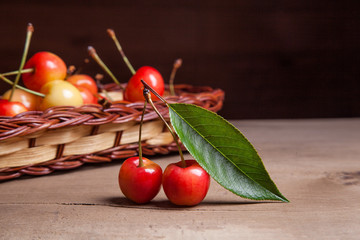 Yellow sweet cherry in basket on wooden background.