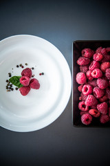 Red raspberry dessert / Fresh ripe fruit served on black and white plates. Flat lay minimalistic...