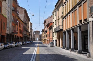 Long road and parked cars with orange buildings in Bologna