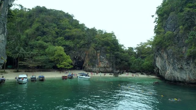 Flying out of bay with boats at beautiful excotic paradise island at krabi region thailand - aerial drone shot