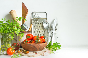 Fresh tomatoes and parsley, dill, garlic on a light background in a rustic kitchen and wooden utensils still life with a copy space