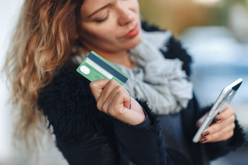 Woman holding a credit card and using cell phone for online shopping. close up