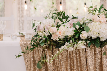 Decoration of a stylish beautiful wedding with flowers and golden fabric with sequins.
