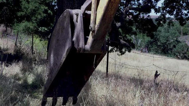 Backhoe tractor digging up a leaking water line on a hot day