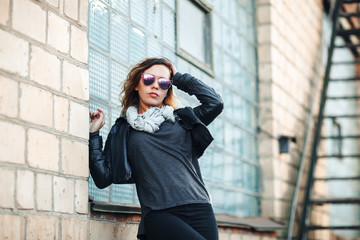 Fototapeta premium model in sunglasses, black leather jacket, jeans. Posing near a red brick wall