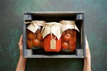 Autumn preserves of tomatoes and vegetable puree in glass jars placed in wooden box. Homemade...