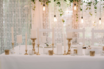 It is a lot of white candles in golden candlesticks of different height.