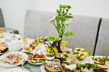 Wedding table with number on it decorated with flowers and covered with huge variety of food.