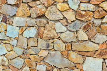 Decorative stone wall, pieces of rock bonded with cement. Cobble texture with cracks. Mountain of castle San Juan. Spanish beach resort Blanes in summertime, Costa Brava, Catalonia, Spain