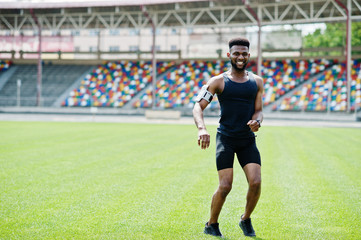 African american male athlete in sportswear doing jump exercise at stadium.