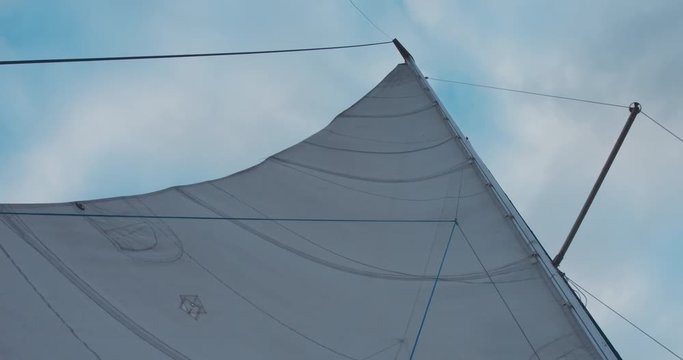 View of mainsail of yacht sailing on a large lake. 4K UHD 60 FPS SLO MO