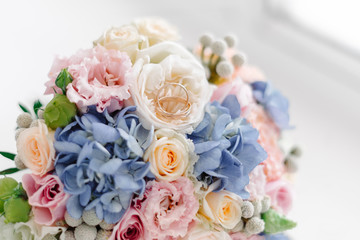 Close up of gold wedding rings on bouquet